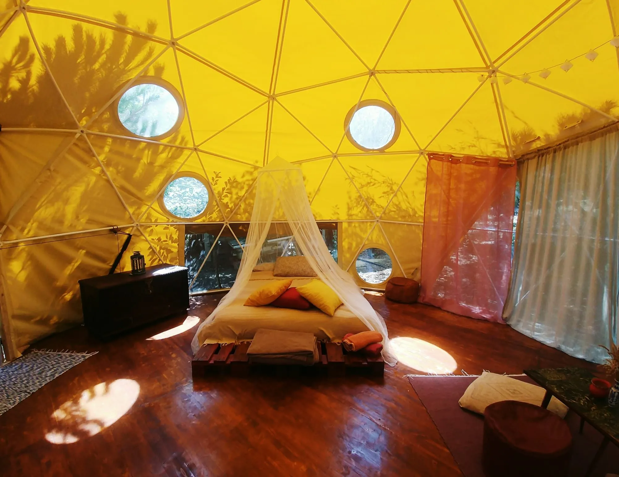 Inside the geodesic dome: a large bed under round windows