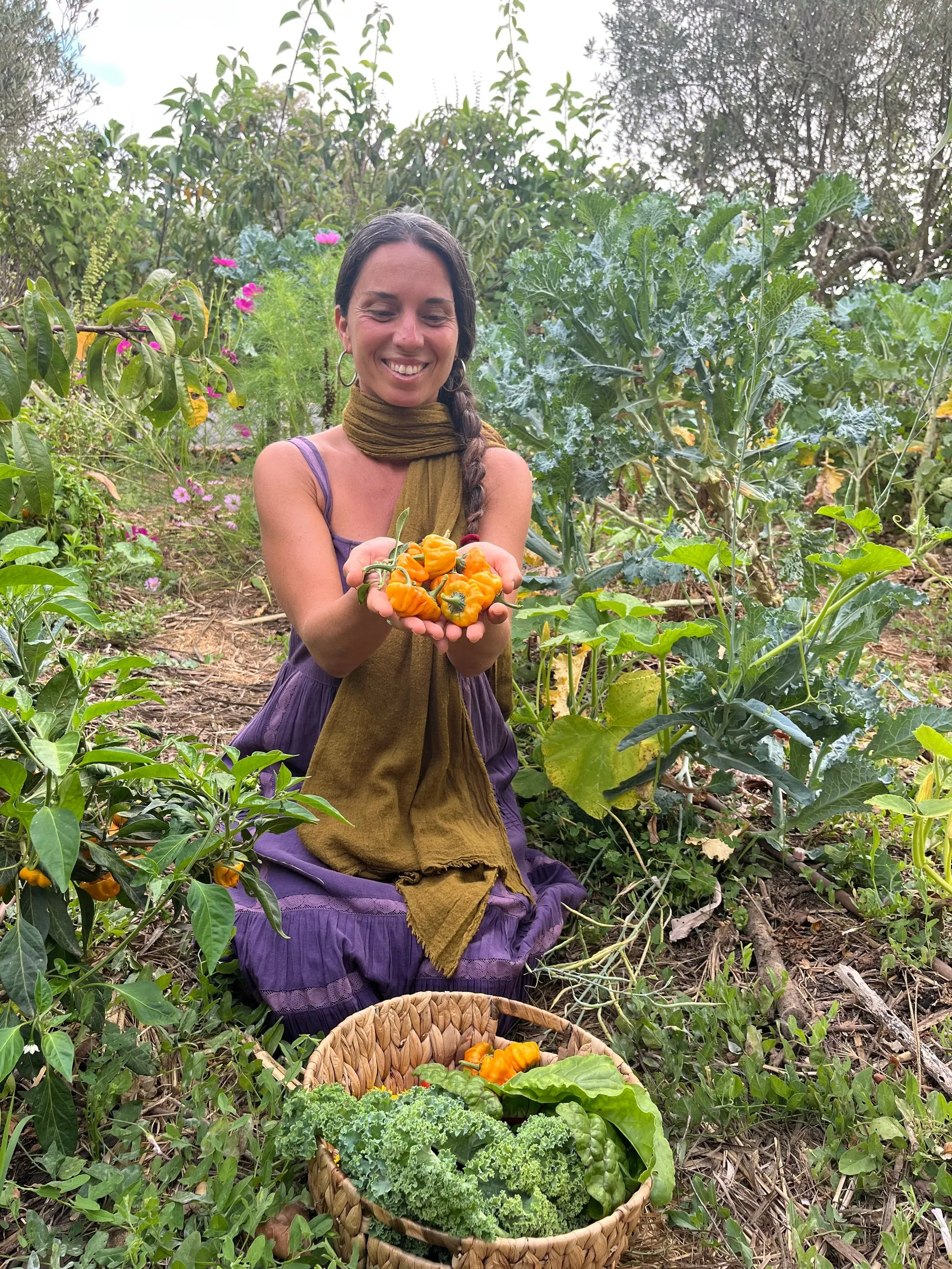 Melania kneeling in the garden with a handful of freshly picked orange flowers